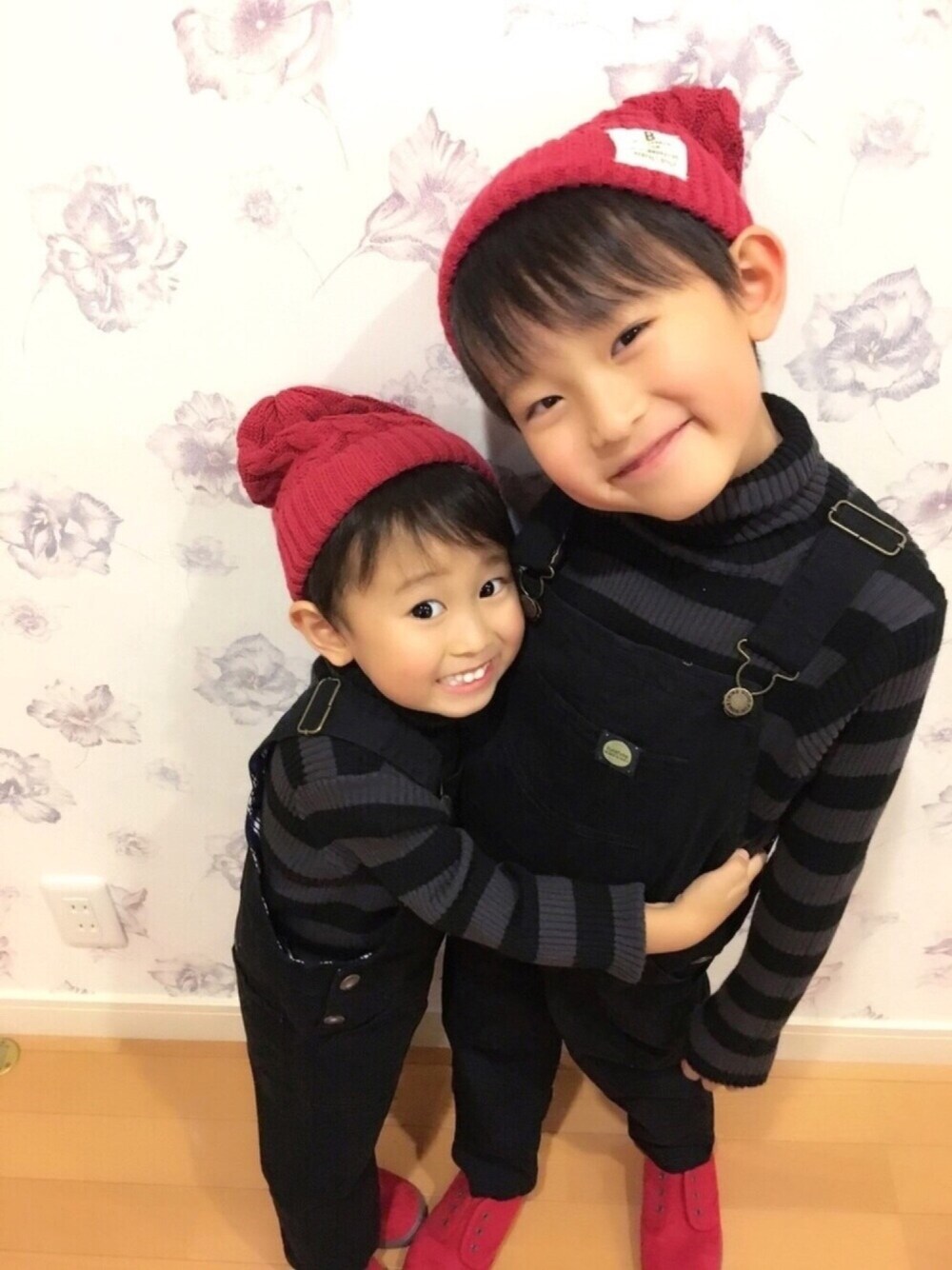 グレー系のニット/セーター、ブラック系のサロペット/オーバーオール、レッド系のスニーカーを着用したキッズの冬コーディネートの1枚目の写真