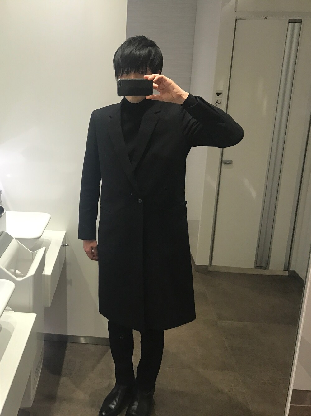 ブラック系のチェスターコート、ブラック系のその他パンツ、ブラック系のブーツを着用したメンズの春コーディネートの1枚目の写真