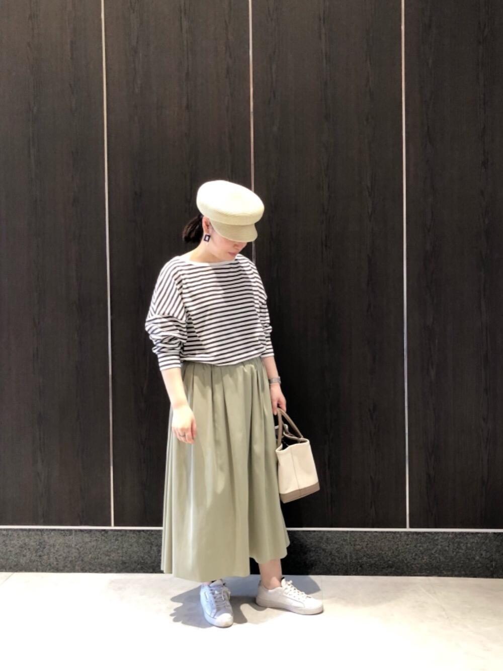 ベージュ系のトートバッグ、グリーン系のスカート、ブラウン系のTシャツ/カットソーを着用したレディースの春コーディネートの1枚目の写真