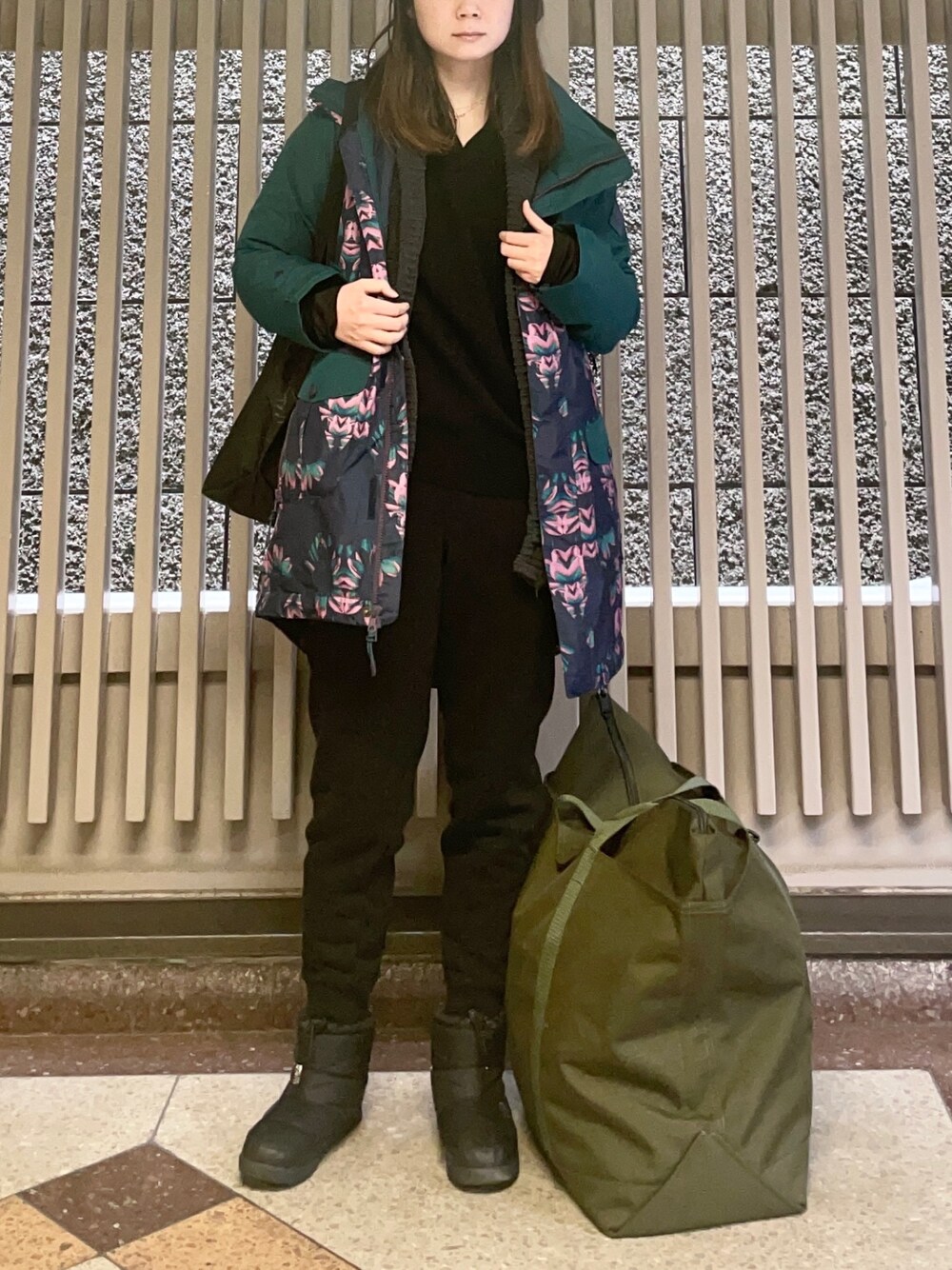 グリーン系のマウンテンパーカー、ブラック系のニット/セーター、ブラック系のスウェットパンツを着用したレディースの春コーディネートの1枚目の写真