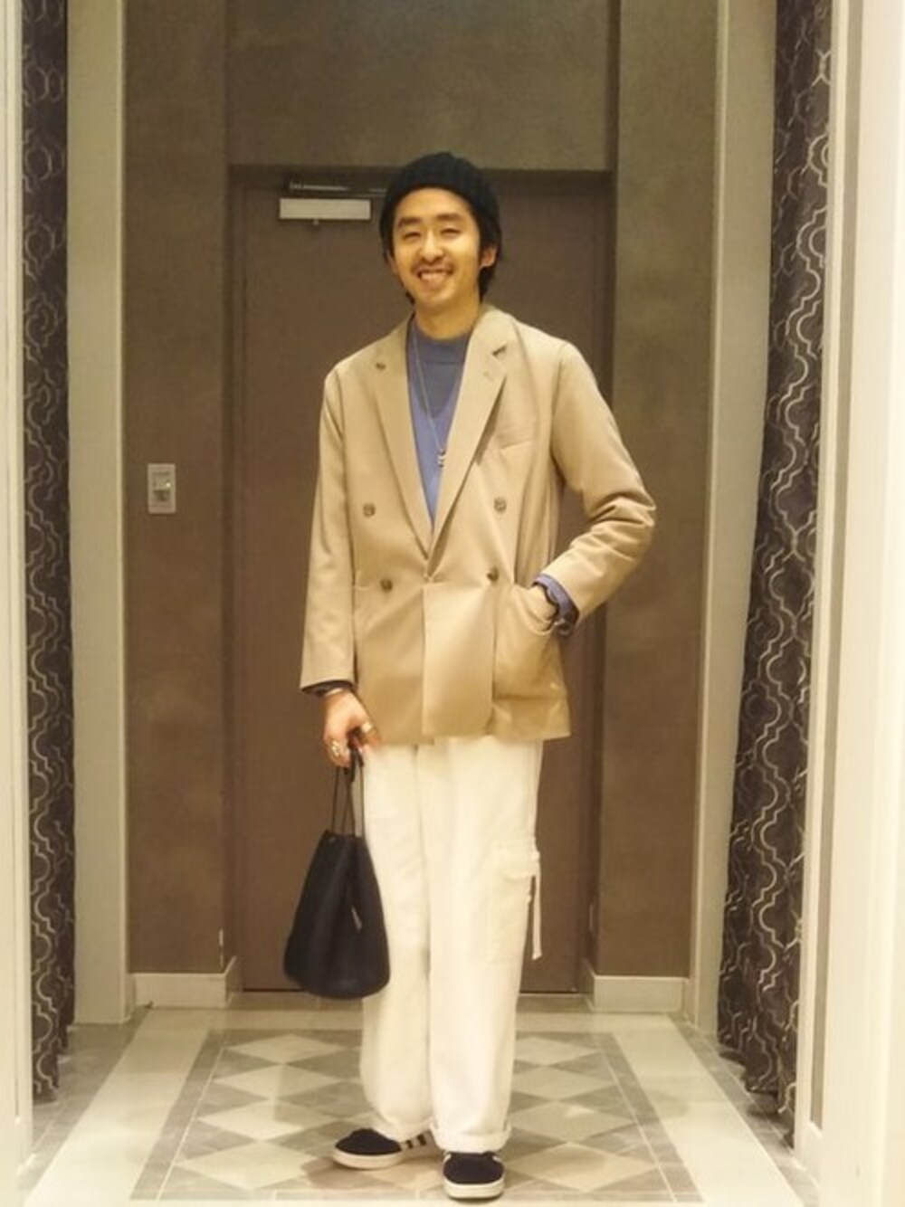 ブラック系のハンドバッグ、ブルー系のニット/セーター、ベージュ系のテーラードジャケットを着用したメンズの冬コーディネートの1枚目の写真