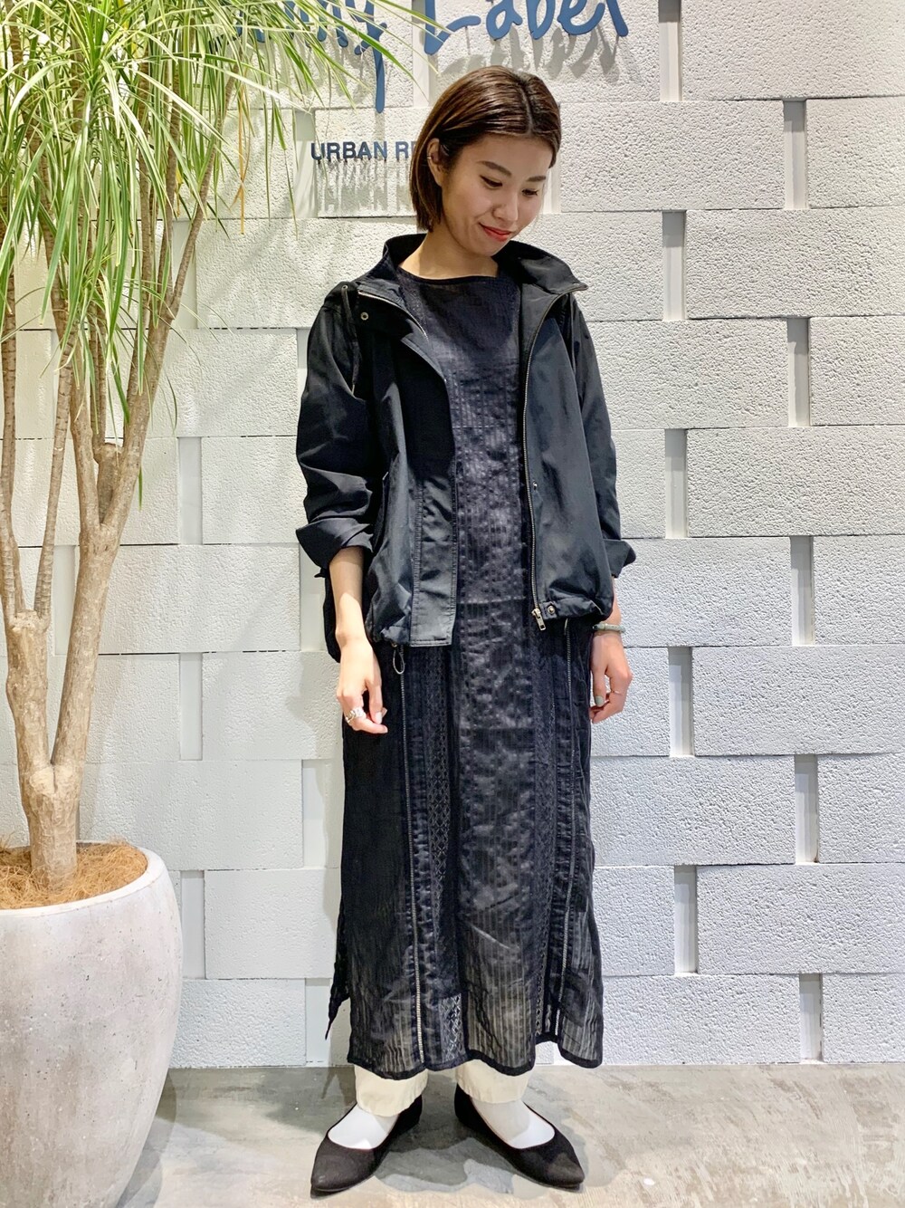 ブラック系のマウンテンパーカー、ブラック系のワンピース、ホワイト系のデニムパンツを着用したレディースの春コーディネートの1枚目の写真