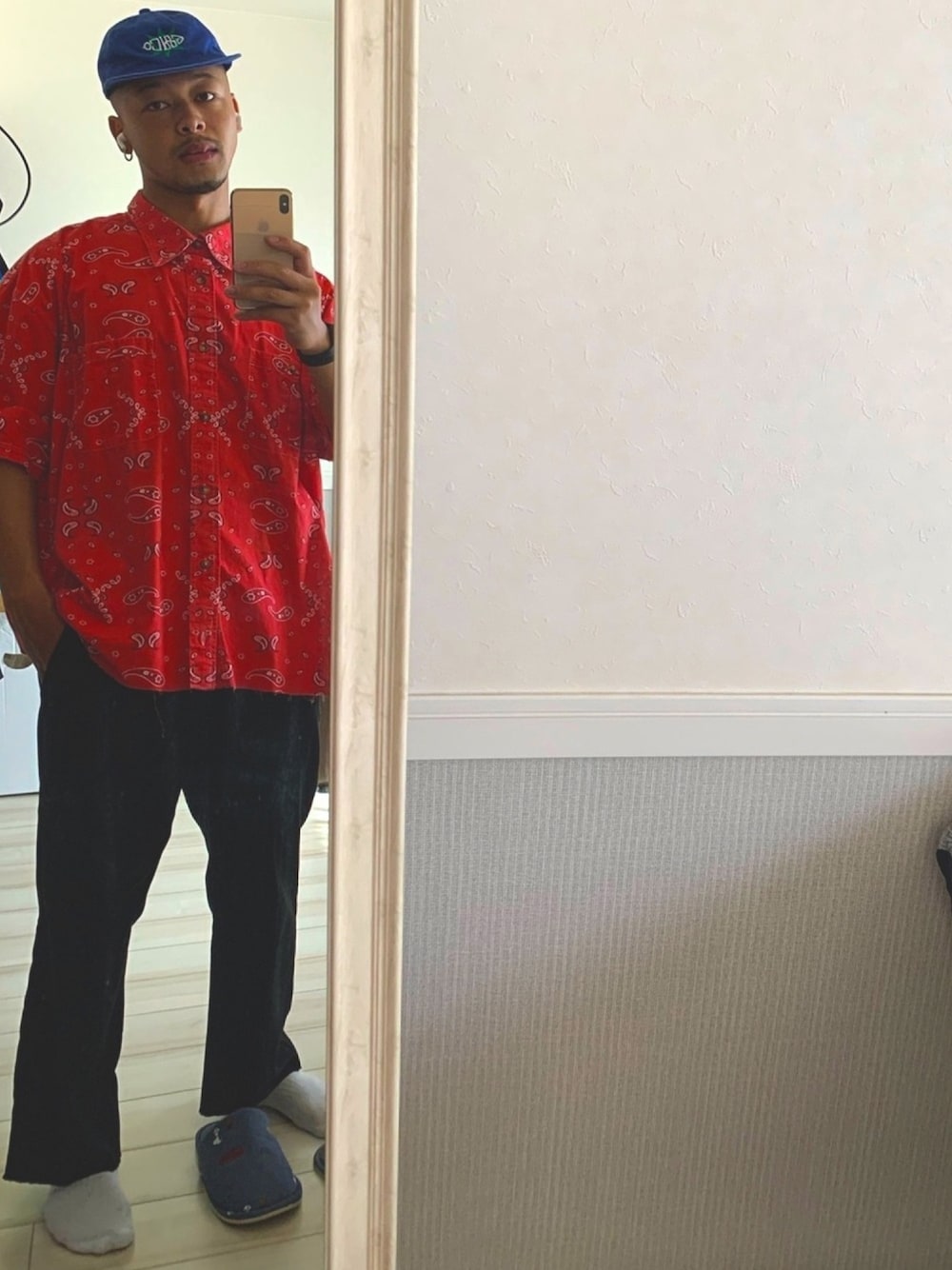 ブラック系のチノパンツ、レッド系のTシャツ/カットソー、ブルー系のキャップを着用したメンズの秋コーディネートの1枚目の写真