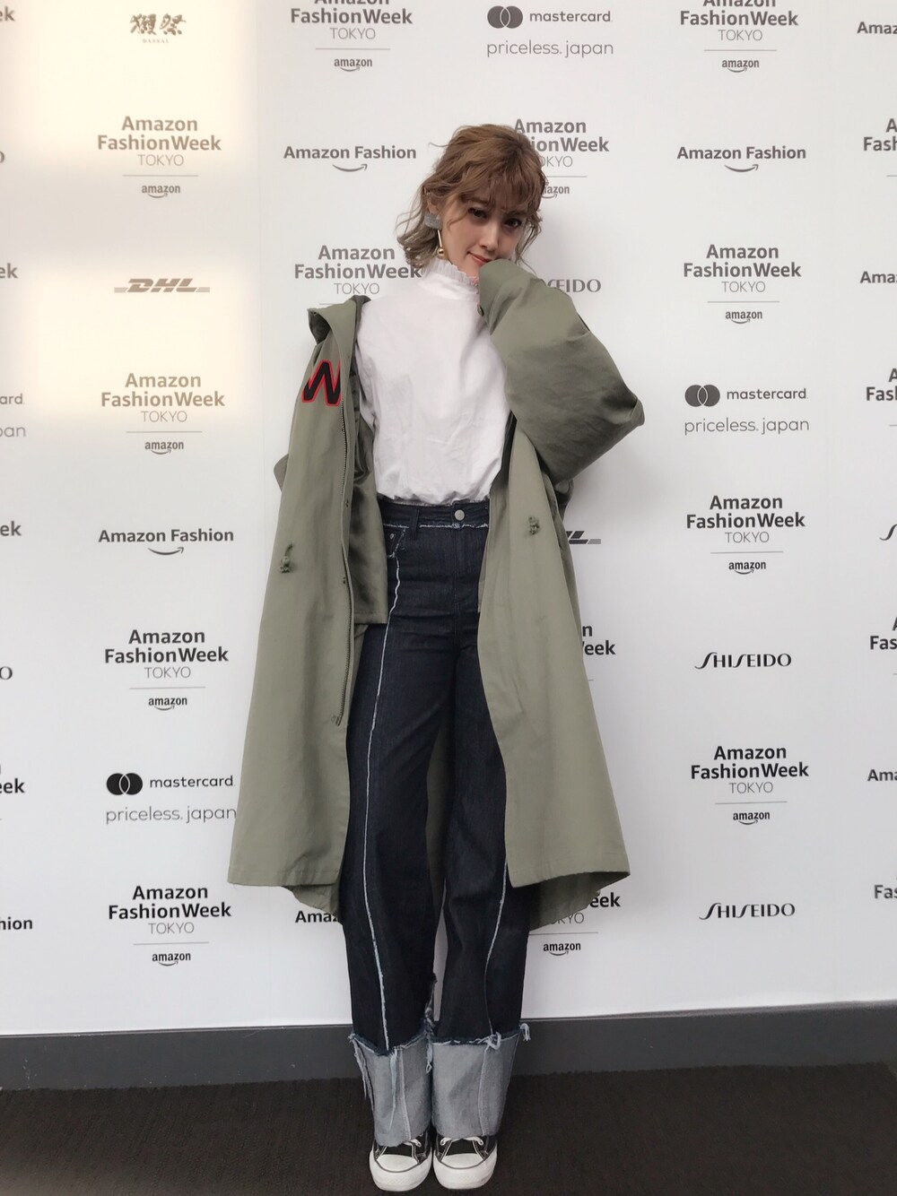 グリーン系のミリタリージャケット、ブルー系のデニムパンツ、ブラック系のスニーカーを着用したレディースの春コーディネートの1枚目の写真