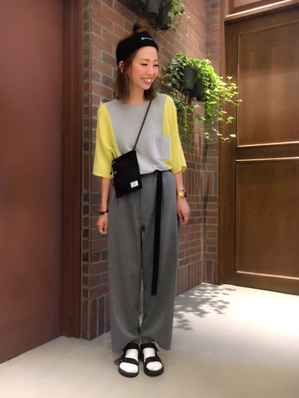 イエロー系のニット/セーター、ブラック系のショルダーバッグ、グレー系のスラックスを着用したレディースの夏コーディネートの1枚目の写真