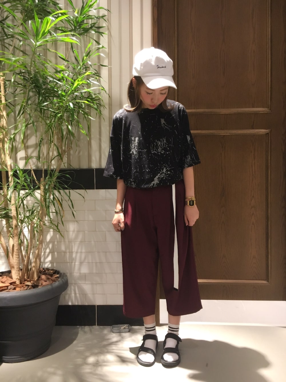 ブラック系のTシャツ/カットソー、レッド系のスラックス、ホワイト系のキャップを着用したレディースの夏コーディネートの1枚目の写真