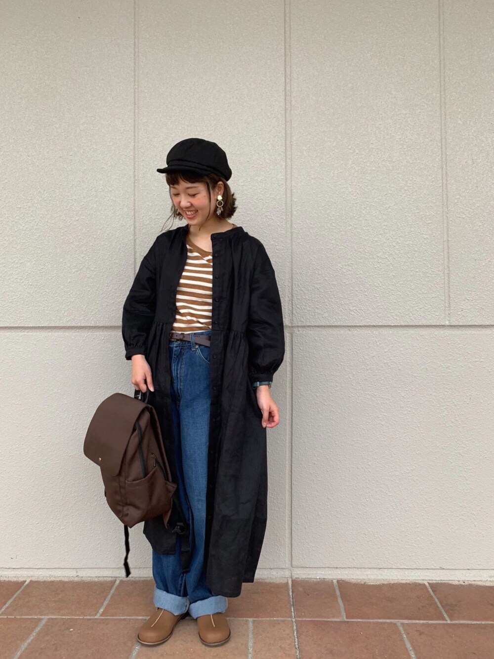 イエロー系のTシャツ/カットソー、ブルー系のデニムパンツ、ブラウン系のバックパック/リュックを着用したレディースの秋コーディネートの1枚目の写真