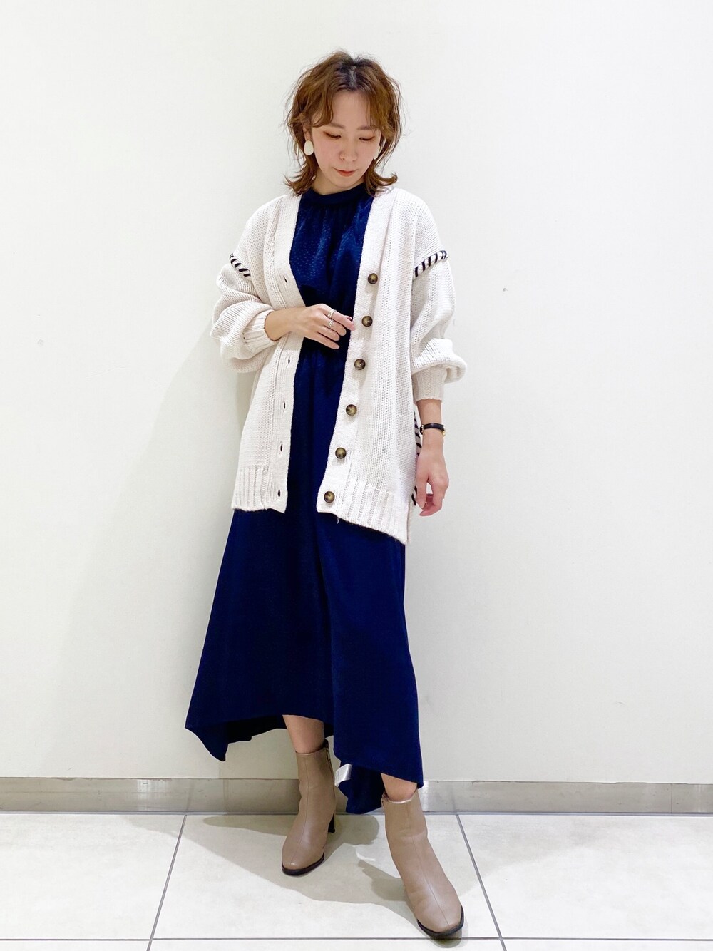 ホワイト系のカーディガン/ボレロ、ブルー系のワンピース、グレー系のブーツを着用したレディースの秋コーディネートの1枚目の写真