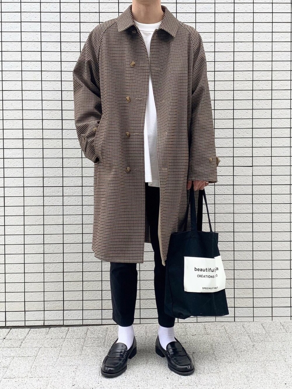 ベージュ系のステンカラーコート、ホワイト系のTシャツ/カットソー、ブラック系のトートバッグを着用したメンズの秋コーディネートの1枚目の写真