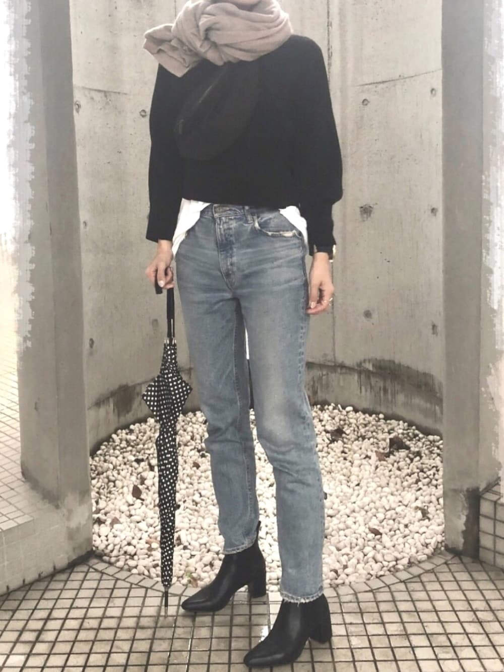 ブラック系のニット/セーター、ブラック系のボディバッグ/ウエストポーチ、ブルー系のデニムパンツを着用したレディースの秋コーディネートの1枚目の写真