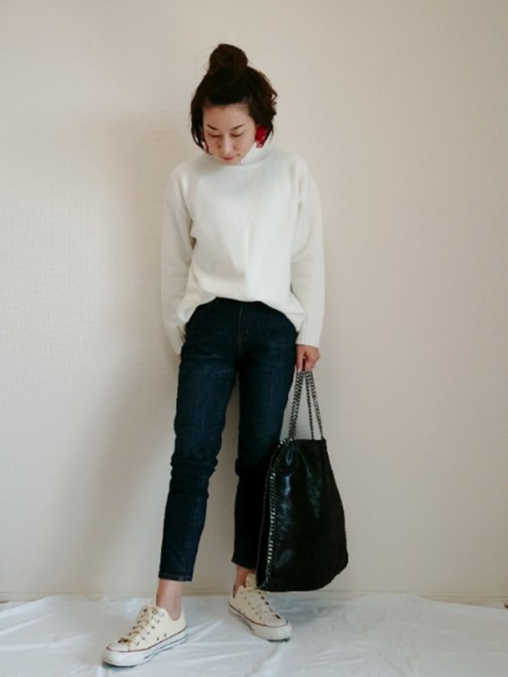 ホワイト系のニット/セーター、ブルー系のデニムパンツ、ベージュ系のスニーカーを着用したレディースの秋コーディネートの1枚目の写真