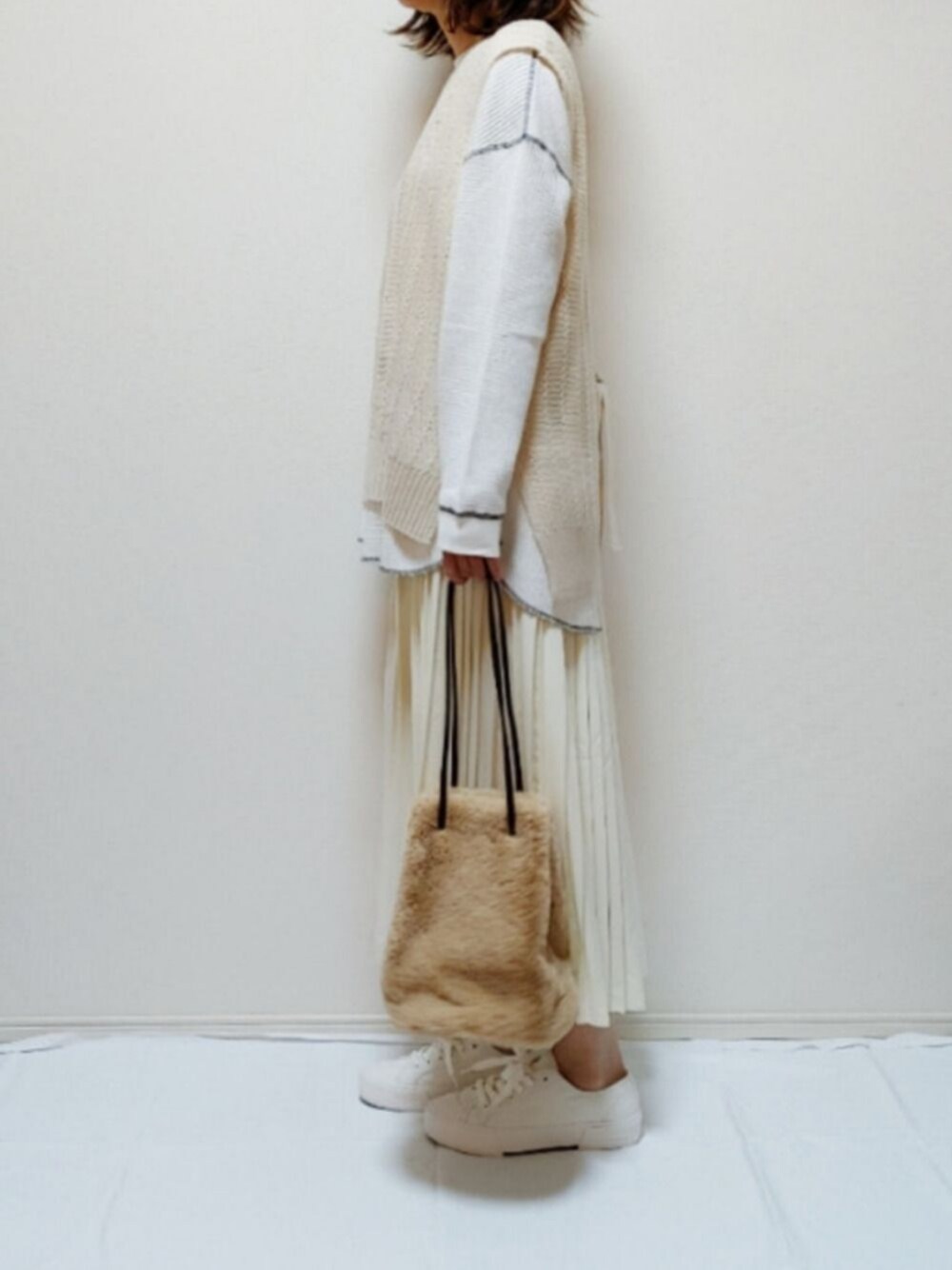 ホワイト系のTシャツ/カットソー、ベージュ系のベスト、ホワイト系のスカートを着用したレディースの秋コーディネートの1枚目の写真