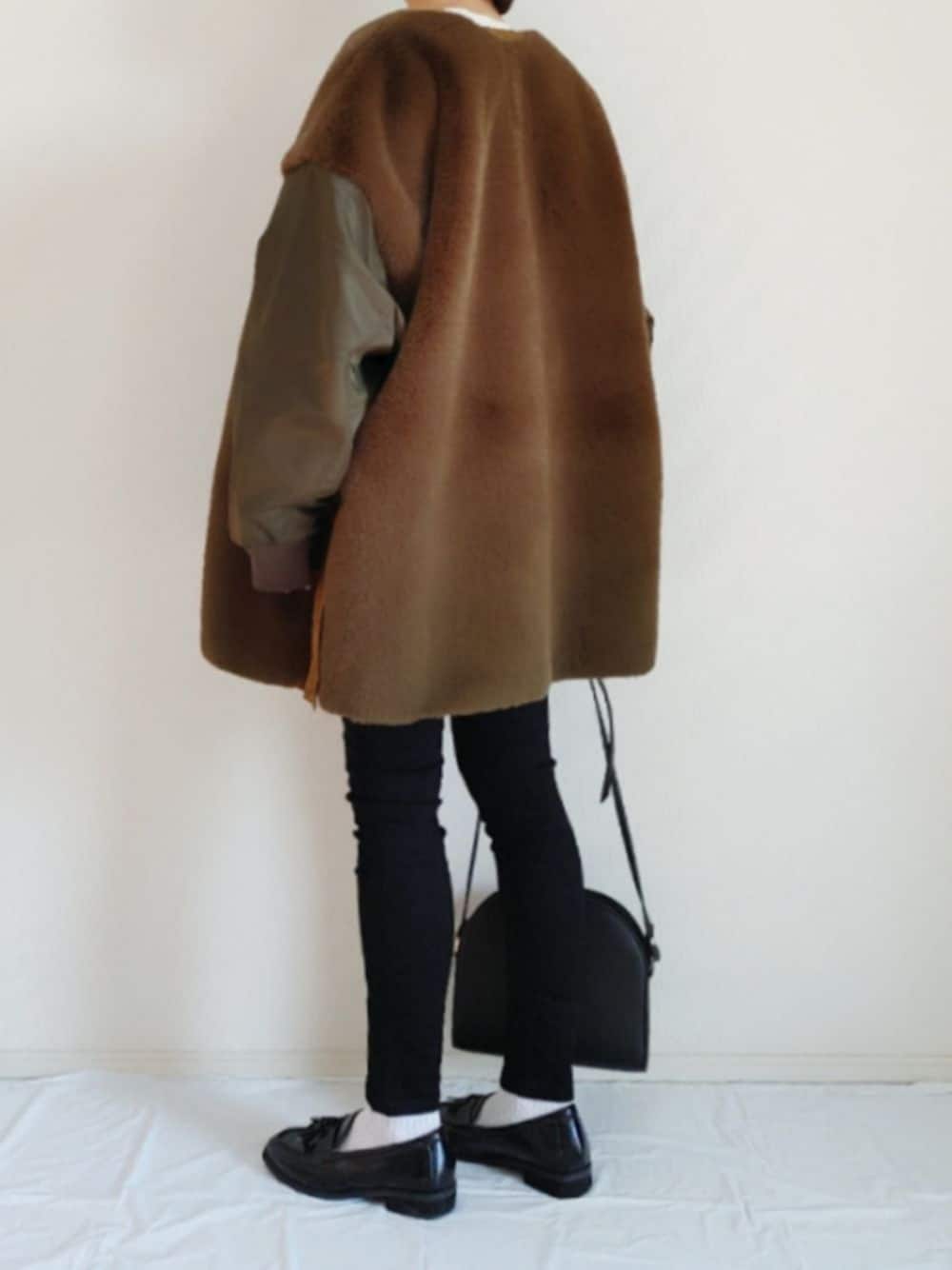 グリーン系のその他アウター、ブラック系のデニムパンツ、ブラック系のローファーを着用したレディースの冬コーディネートの1枚目の写真