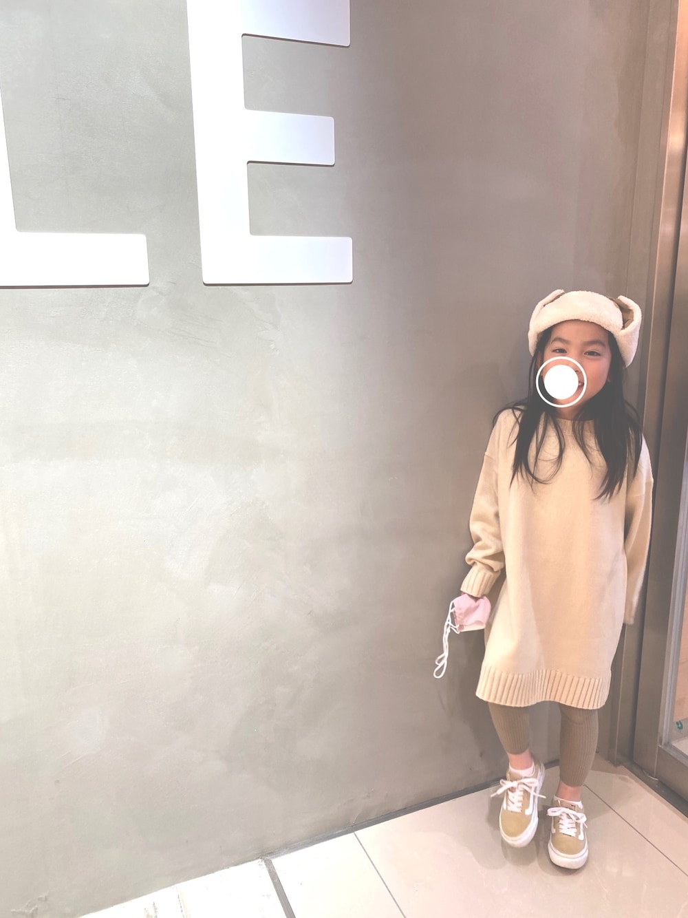 ベージュ系のワンピース、ベージュ系のキャップを着用したキッズの秋コーディネートの1枚目の写真
