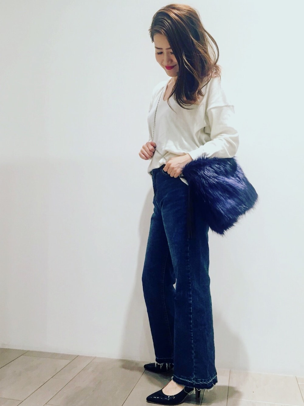 ブルー系のデニムパンツ、ホワイト系のニット/セーター、ブルー系のショルダーバッグを着用したレディースの秋コーディネートの1枚目の写真