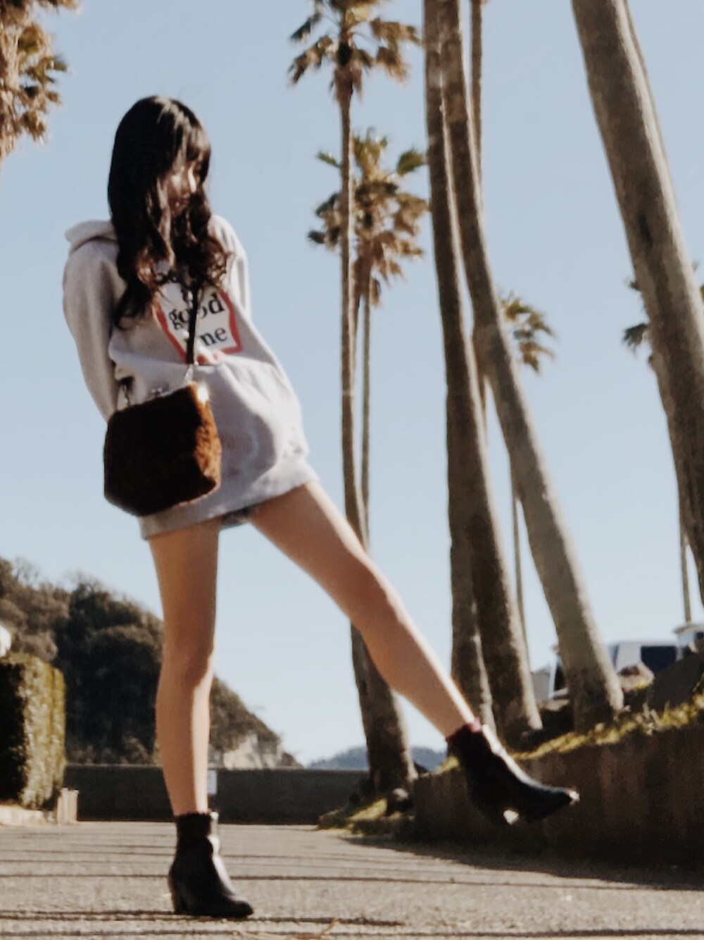 グレー系のパーカー、ブラック系のブーツ、ブラウン系のショルダーバッグを着用したレディースの冬コーディネートの1枚目の写真