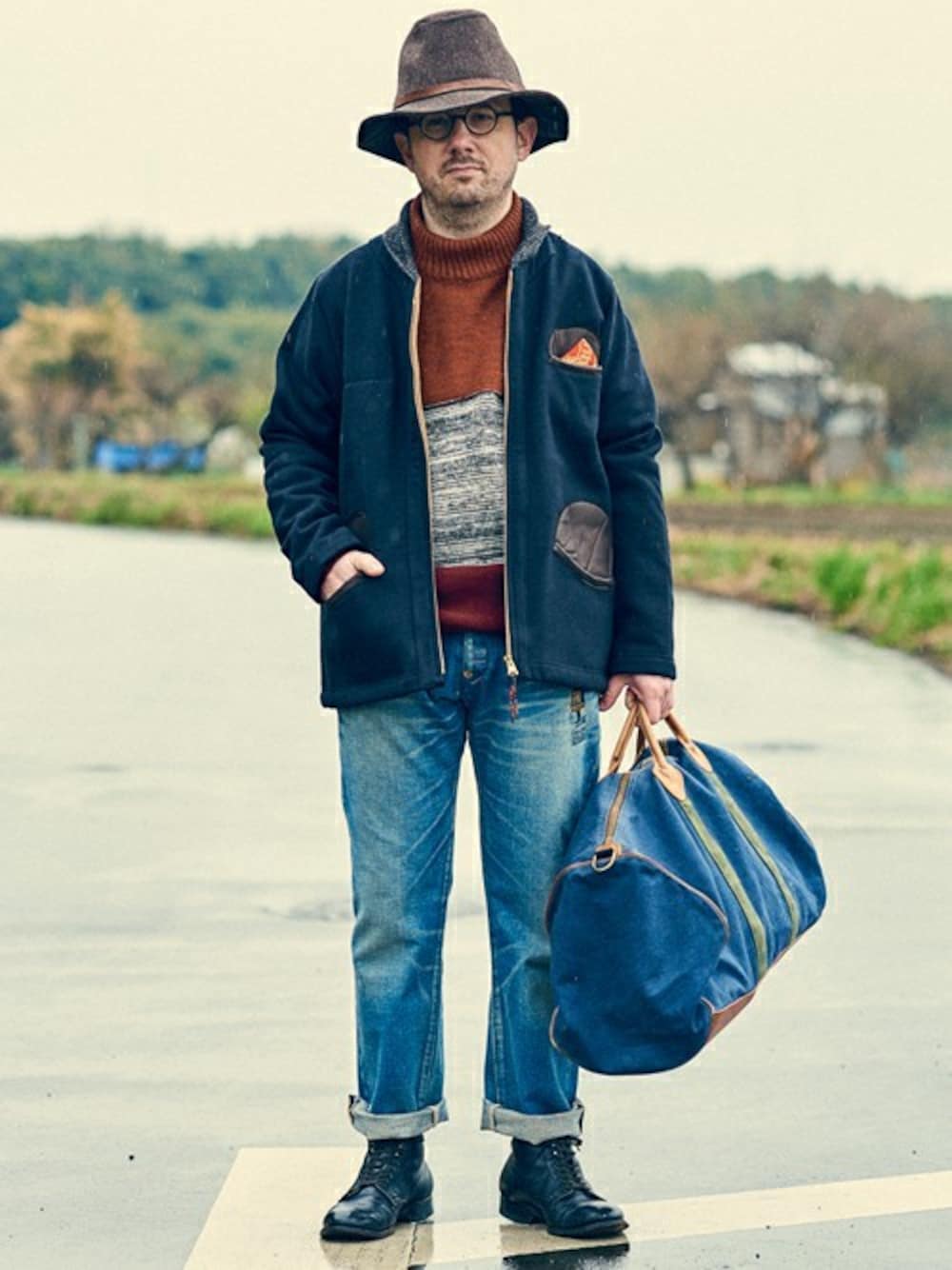 ブラック系のブルゾン、レッド系のニット/セーター、ブルー系のデニムパンツを着用したメンズの冬コーディネートの1枚目の写真