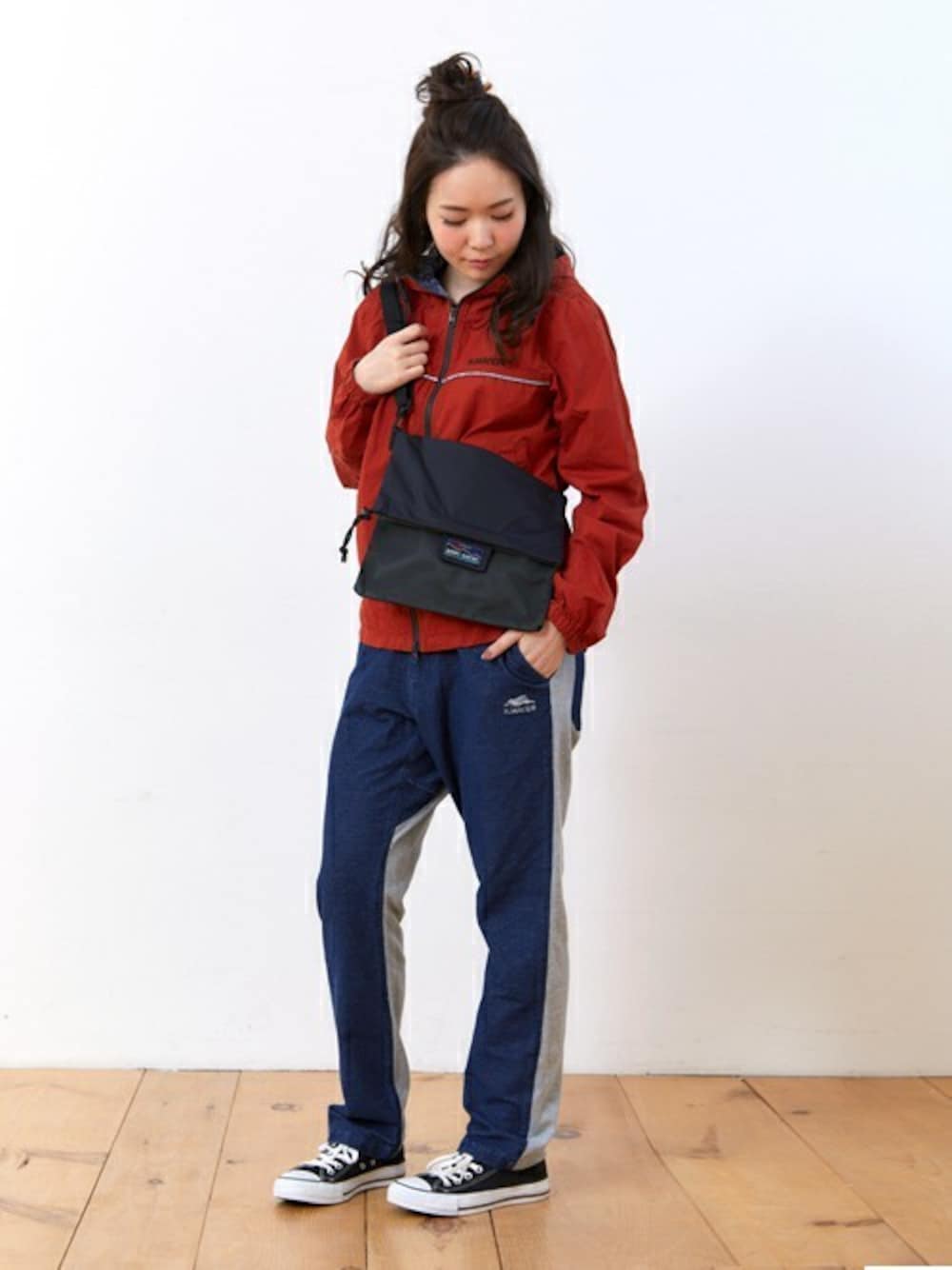 レッド系のマウンテンパーカー、ブルー系のその他パンツ、ブラック系のショルダーバッグを着用したレディースの春コーディネートの1枚目の写真