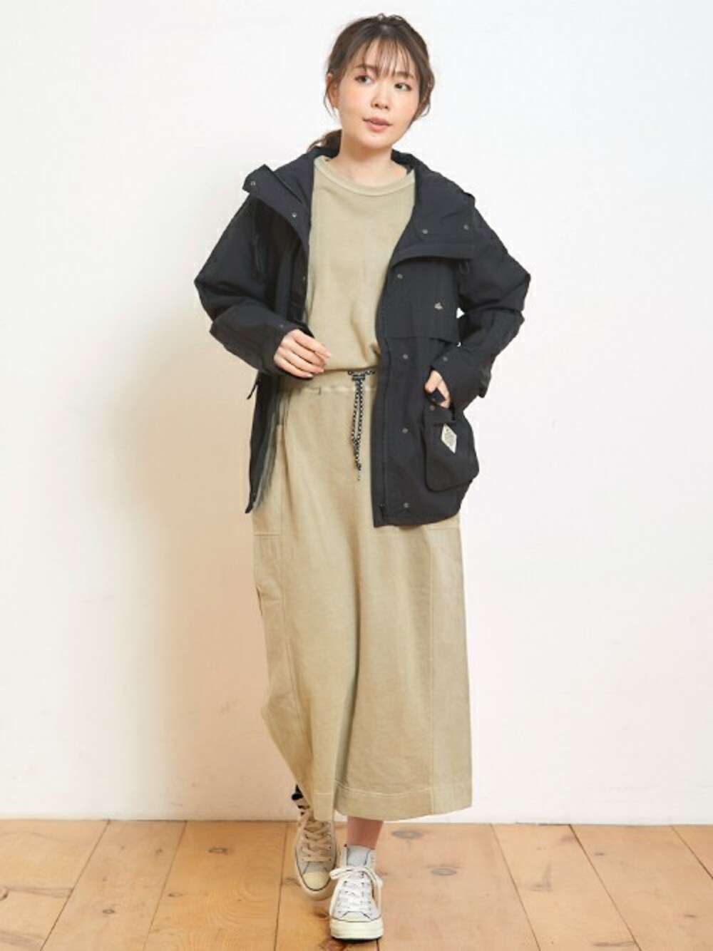 ブラック系のマウンテンパーカー、ベージュ系のTシャツ/カットソー、ベージュ系のスカートを着用したレディースの春コーディネートの1枚目の写真