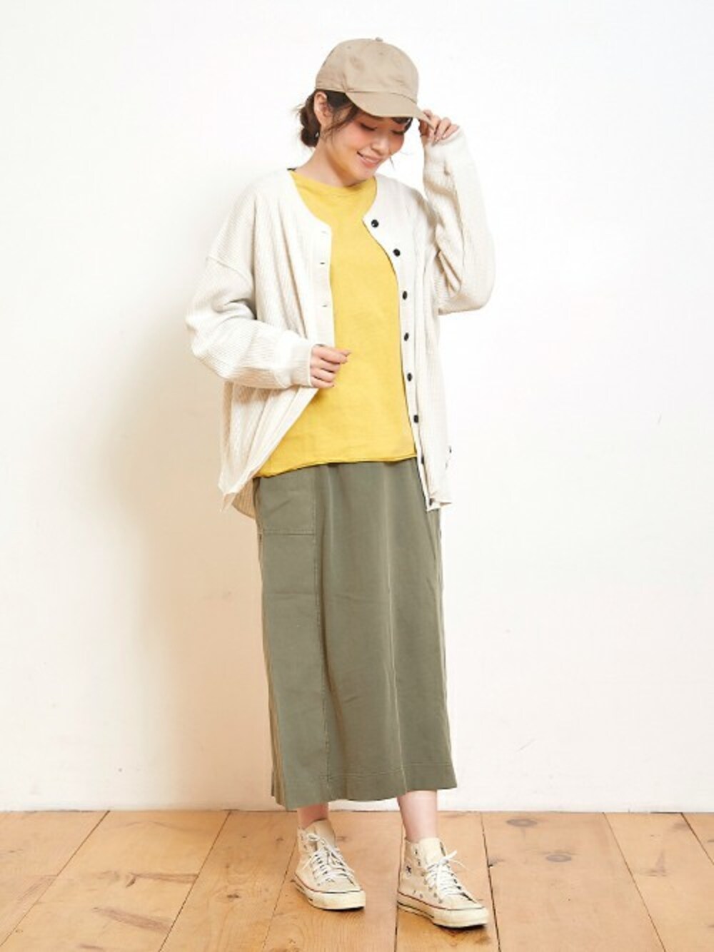 イエロー系のTシャツ/カットソー、グリーン系のスカート、ホワイト系のカーディガン/ボレロを着用したレディースの春コーディネートの1枚目の写真