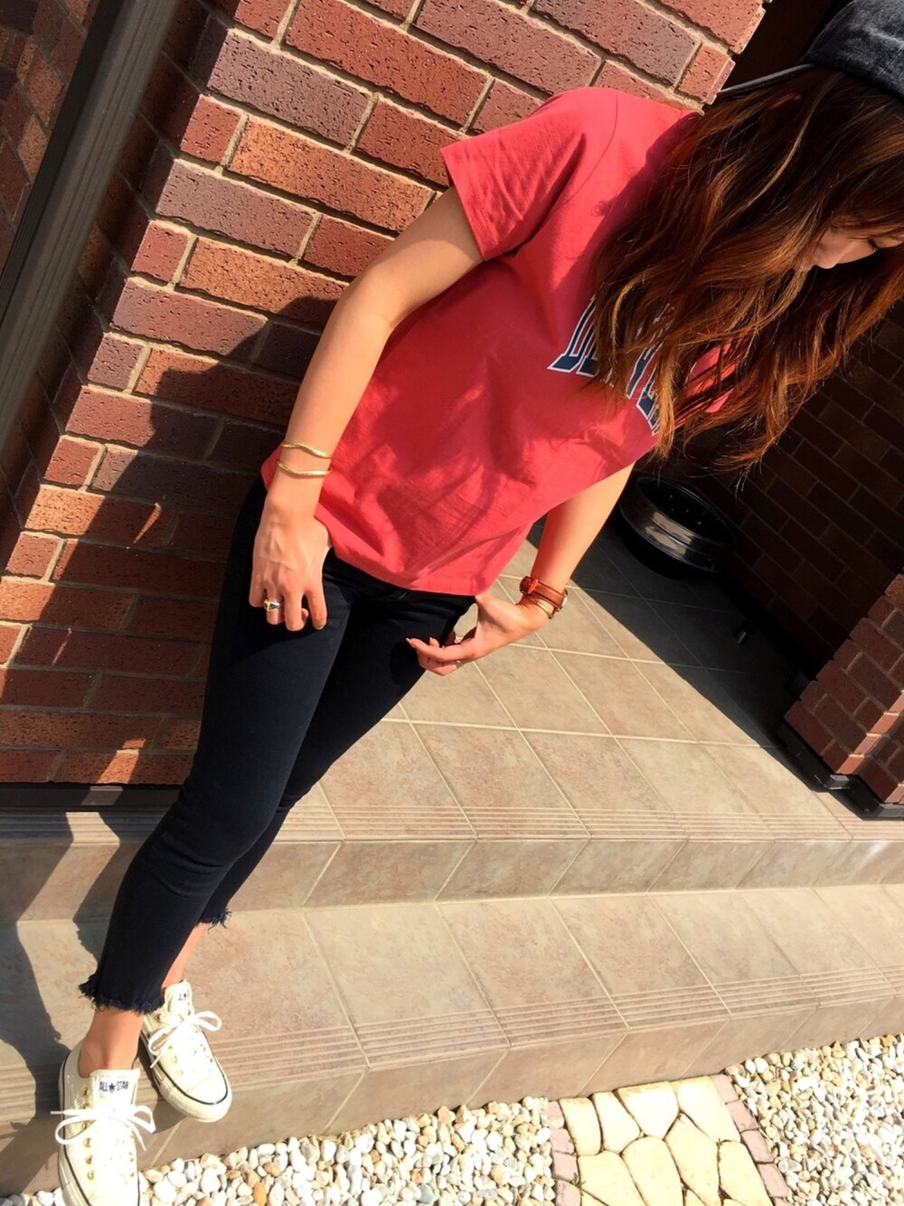 レッド系のTシャツ/カットソー、ブラック系のデニムパンツ、ベージュ系のスニーカーを着用したレディースの春コーディネートの1枚目の写真