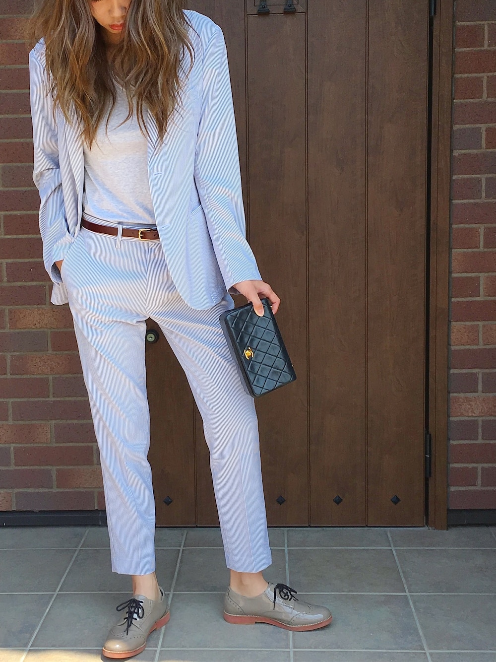 ホワイト系のスラックス、ホワイト系のテーラードジャケット、ブラック系のショルダーバッグを着用したレディースの夏コーディネートの1枚目の写真