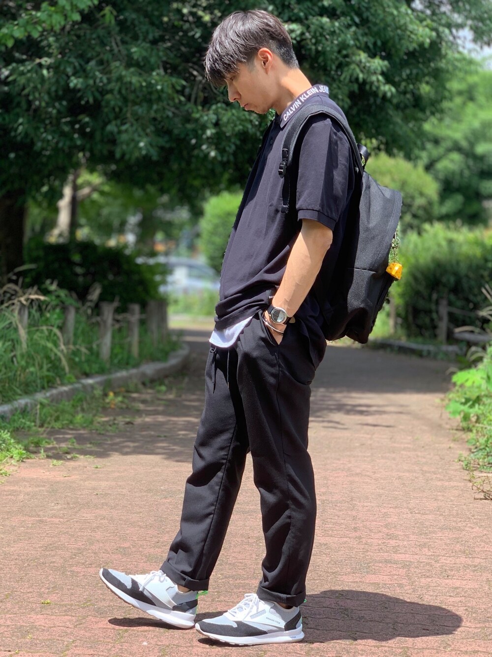 ブラック系のポロシャツ、ホワイト系のタンクトップ、その他のバックパック/リュックを着用したメンズの夏コーディネートの1枚目の写真
