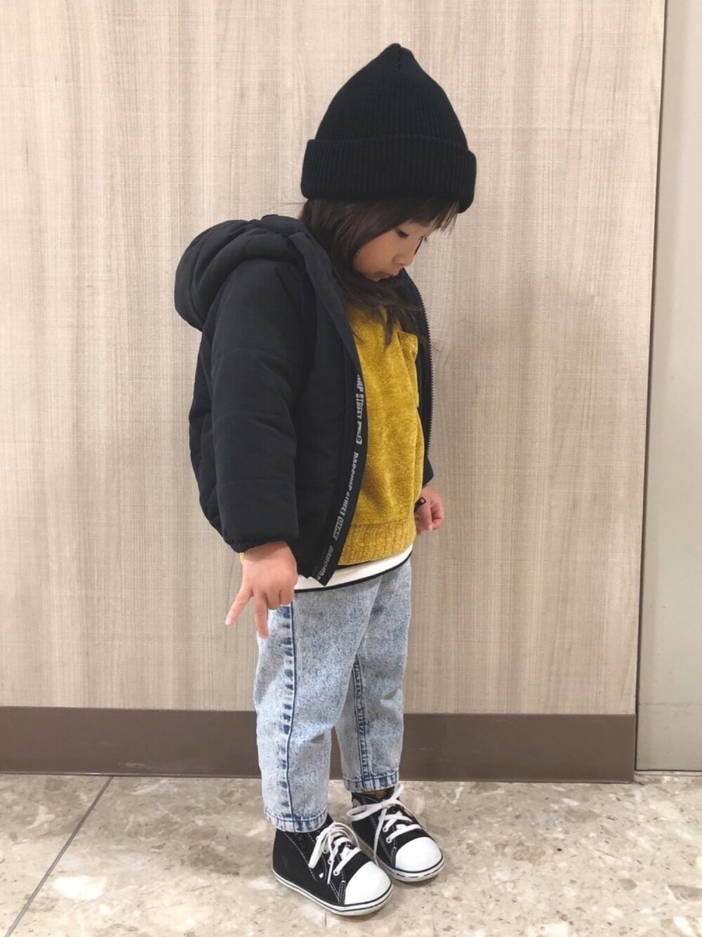 ブラック系のダウンジャケット/コート、イエロー系のニット/セーター、ホワイト系のTシャツ/カットソーを着用したキッズの冬コーディネートの1枚目の写真