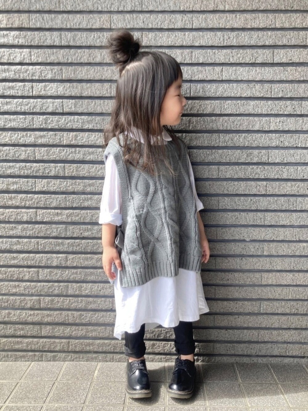 ホワイト系のワンピース、グレー系のベスト、ブラック系のその他パンツを着用したキッズの秋コーディネートの1枚目の写真