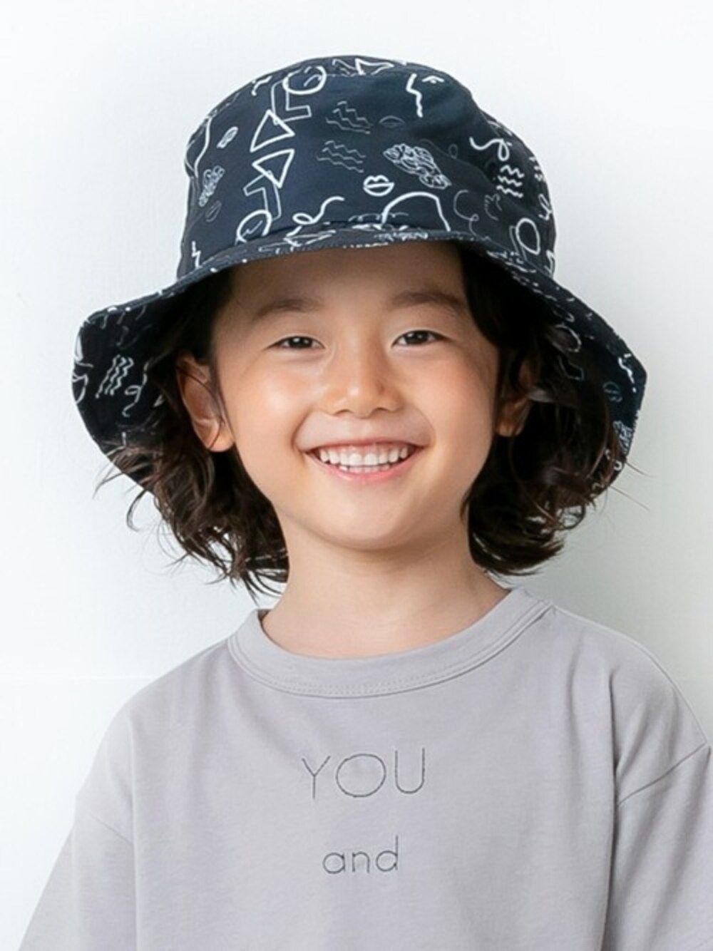 グレー系のTシャツ/カットソー、ブラック系のハットを着用したキッズの春コーディネートの1枚目の写真