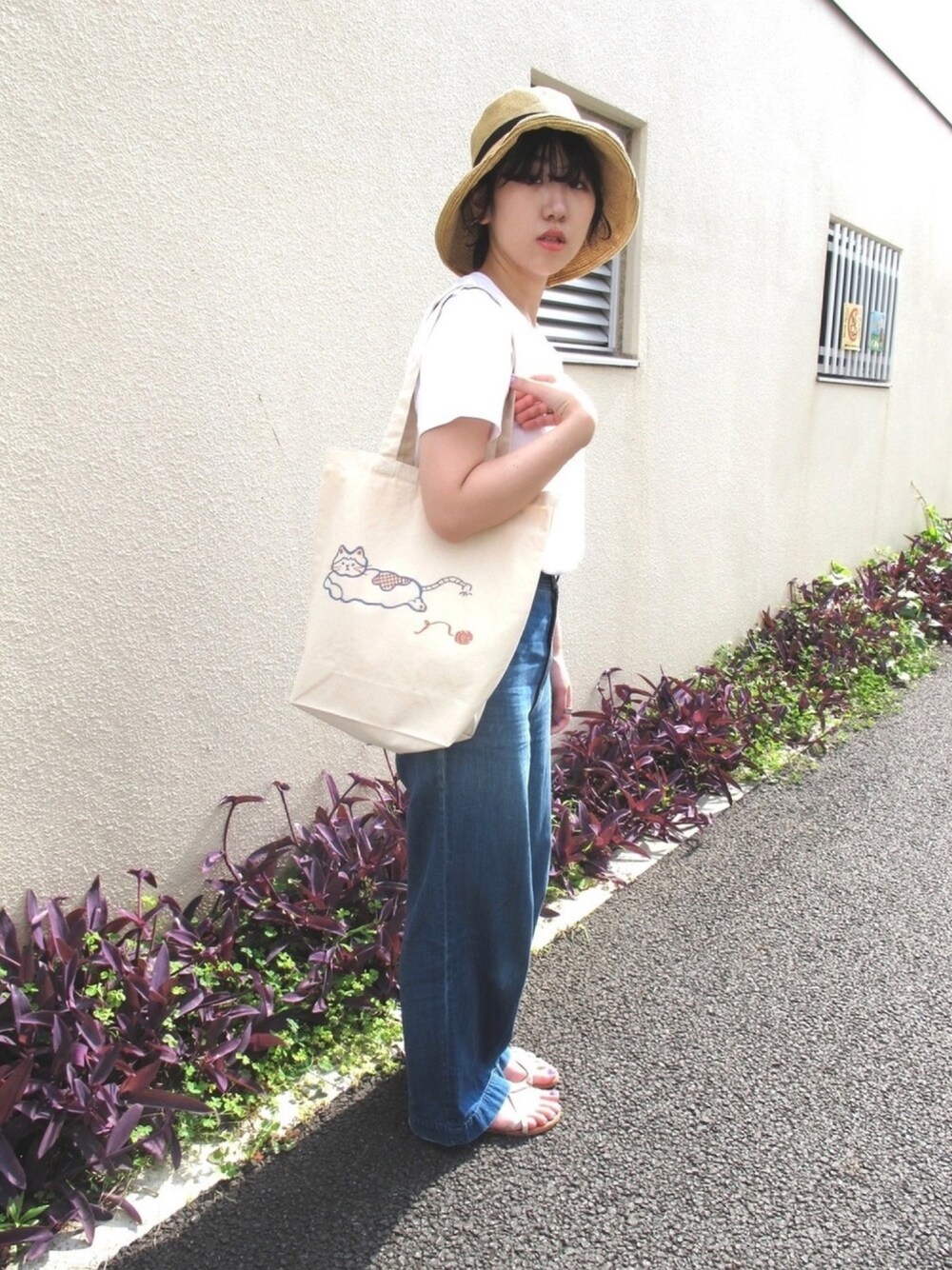 ベージュ系のトートバッグ、ホワイト系のTシャツ/カットソー、ブルー系のデニムパンツを着用したレディースの夏コーディネートの1枚目の写真