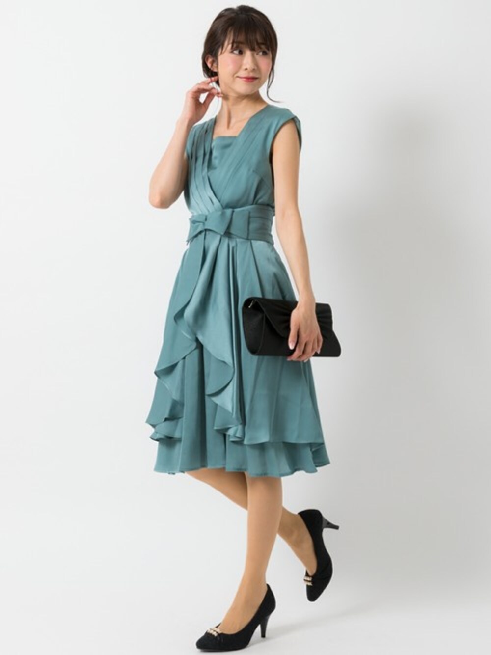 グリーン系のドレス、ブラック系のパンプスを着用したレディースの春コーディネートの1枚目の写真