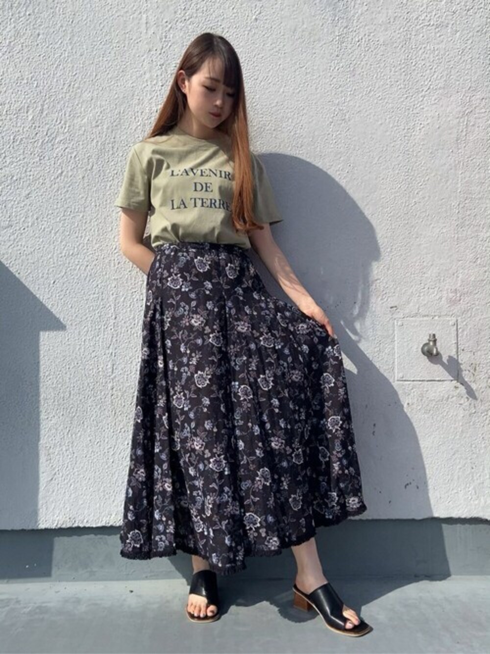 パープル系のスカート、グリーン系のTシャツ/カットソー、ブラック系のサンダルを着用したレディースの春コーディネートの1枚目の写真