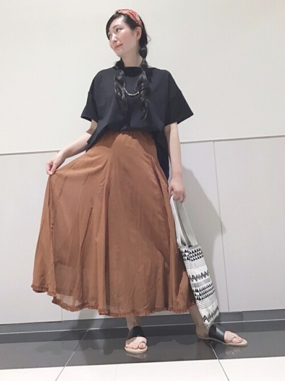 ブラック系のTシャツ/カットソー、ブラウン系のスカート、ホワイト系のトートバッグを着用したレディースの夏コーディネートの1枚目の写真