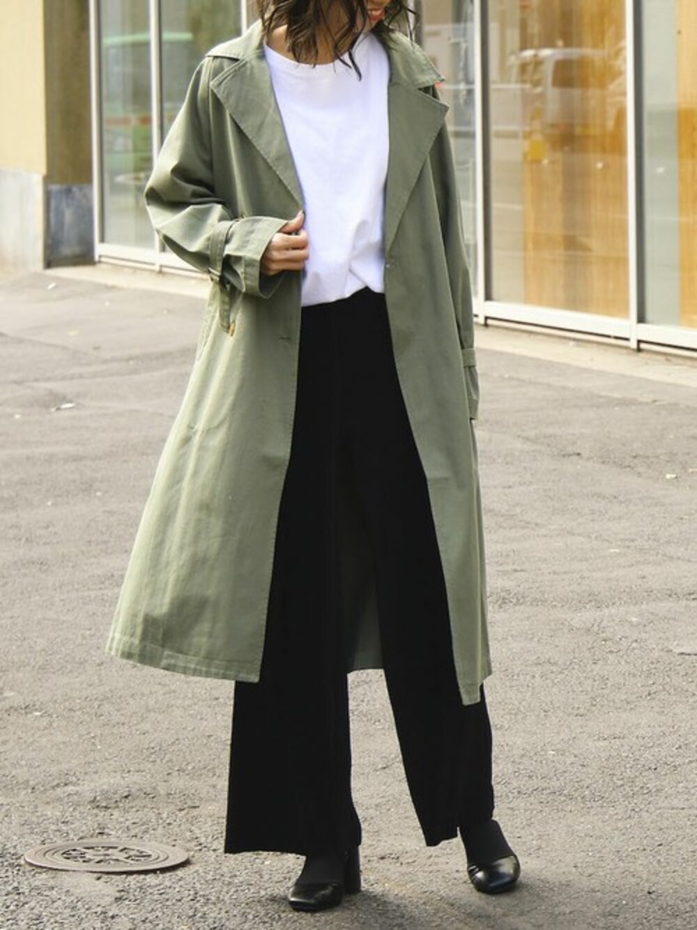 ブラック系のその他パンツ、ホワイト系のチュニック、グリーン系のトレンチコートを着用したレディースの春コーディネートの1枚目の写真