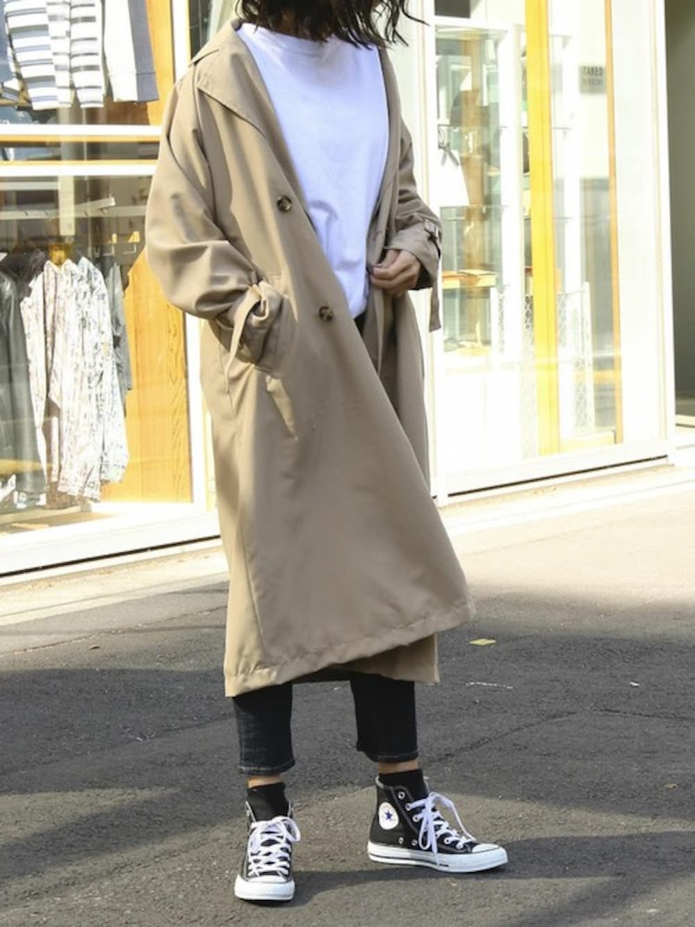 ホワイト系のチュニック、ベージュ系のトレンチコートを着用したレディースの春コーディネートの1枚目の写真