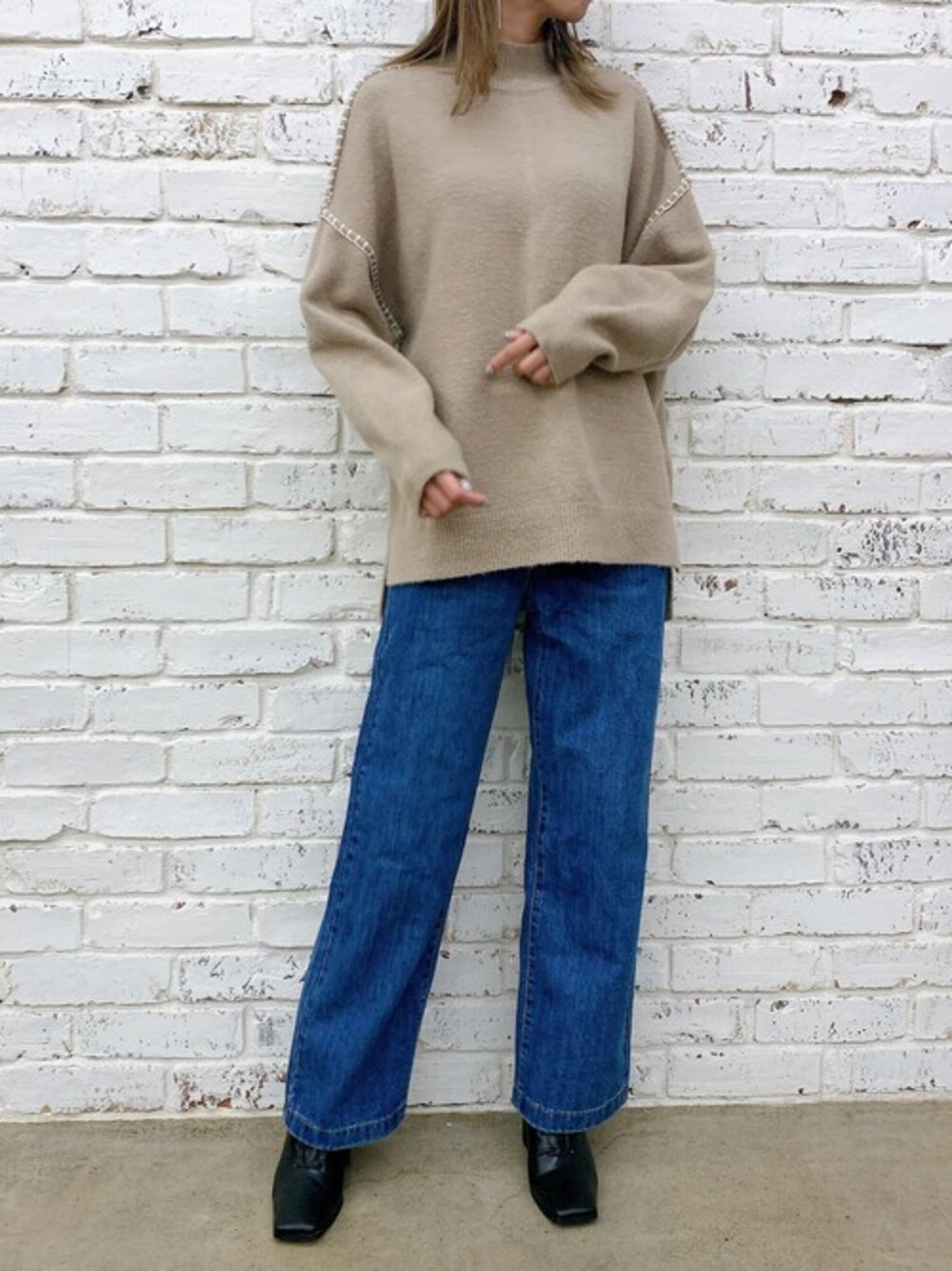 ベージュ系のニット/セーター、ブラック系のブーツ、ブルー系のデニムパンツを着用したレディースの秋コーディネートの1枚目の写真