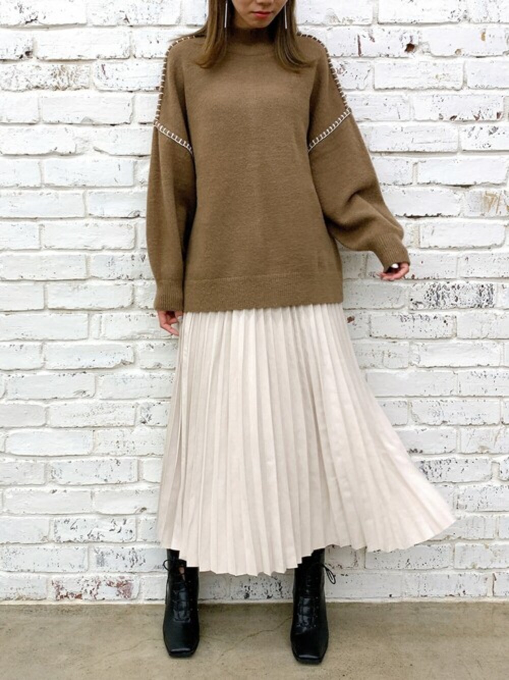ホワイト系のスカート、ブラウン系のニット/セーター、ブラック系のブーツを着用したレディースの冬コーディネートの1枚目の写真