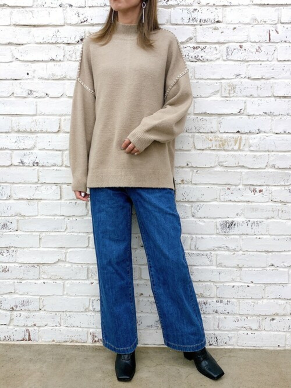 ベージュ系のニット/セーター、ブルー系のデニムパンツ、ブラック系のブーツを着用したレディースの冬コーディネートの1枚目の写真