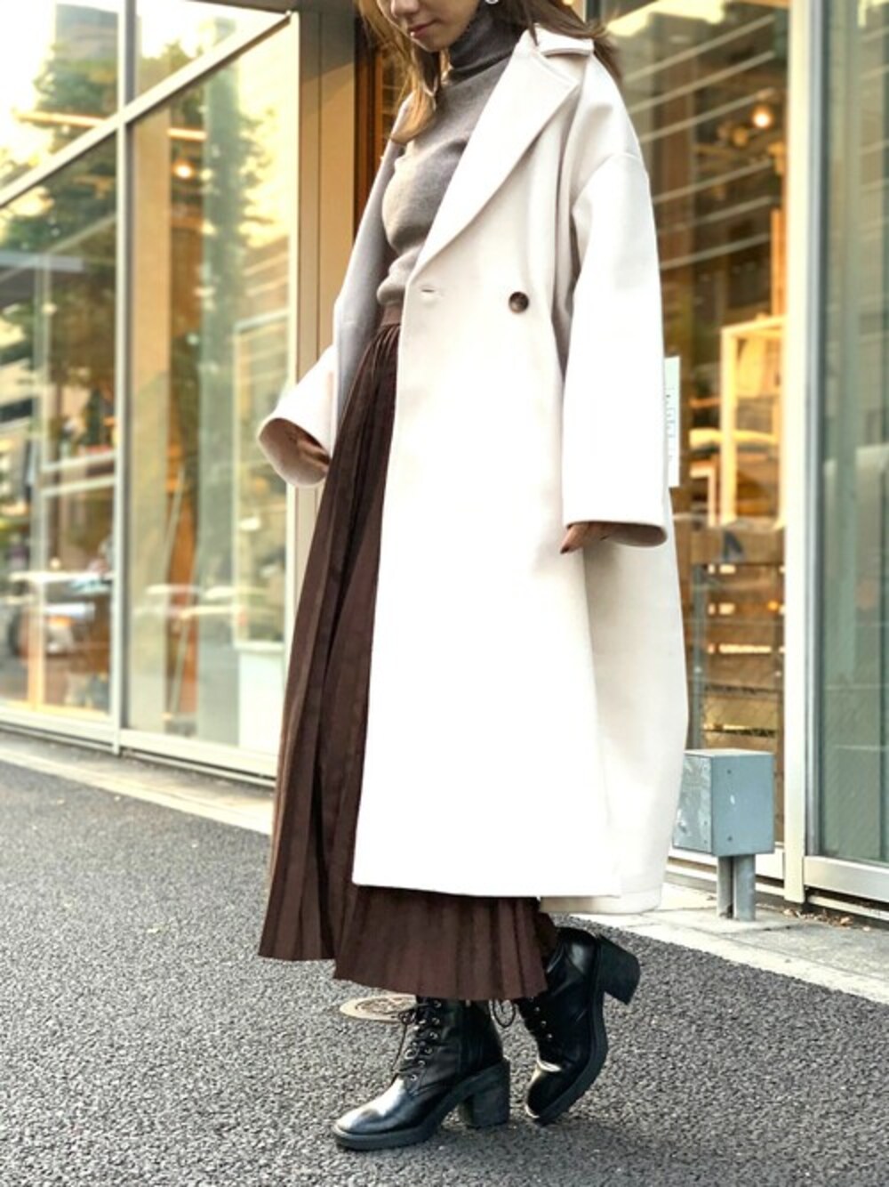 ブラウン系のニット/セーター、ホワイト系のチェスターコート、ブラウン系のスカートを着用したレディースの冬コーディネートの1枚目の写真