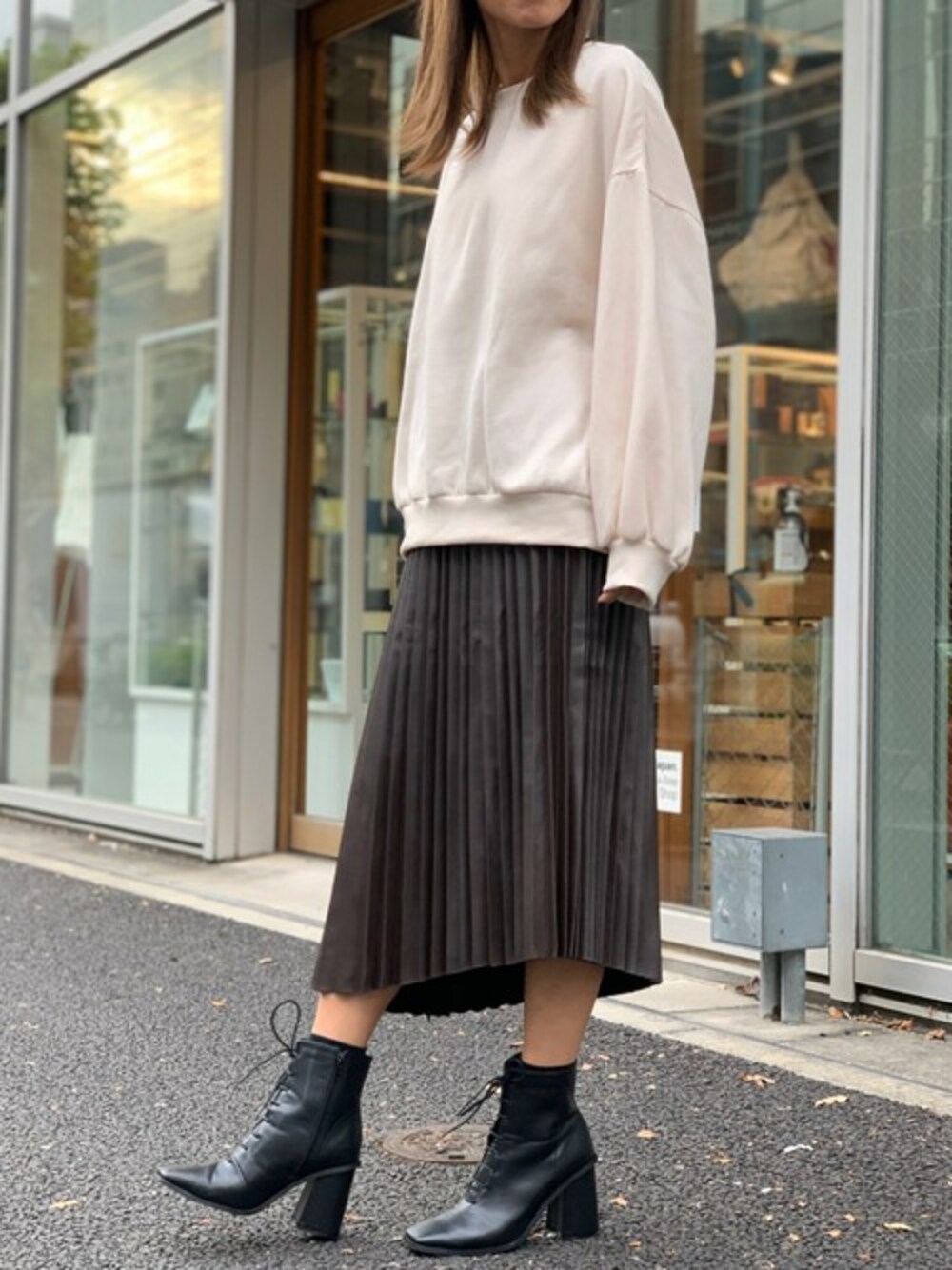 ホワイト系のスウェット、ブラウン系のスカート、ブラック系のブーツを着用したレディースの冬コーディネートの1枚目の写真