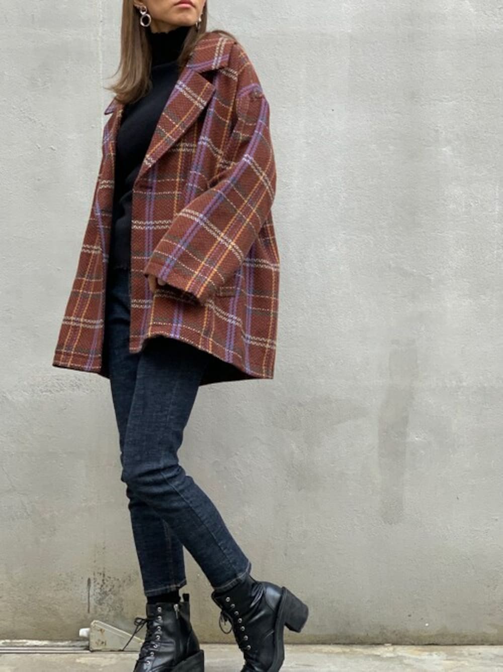 オレンジ系のチェスターコート、ブラック系のニット/セーター、ブラック系のブーツを着用したレディースの冬コーディネートの1枚目の写真