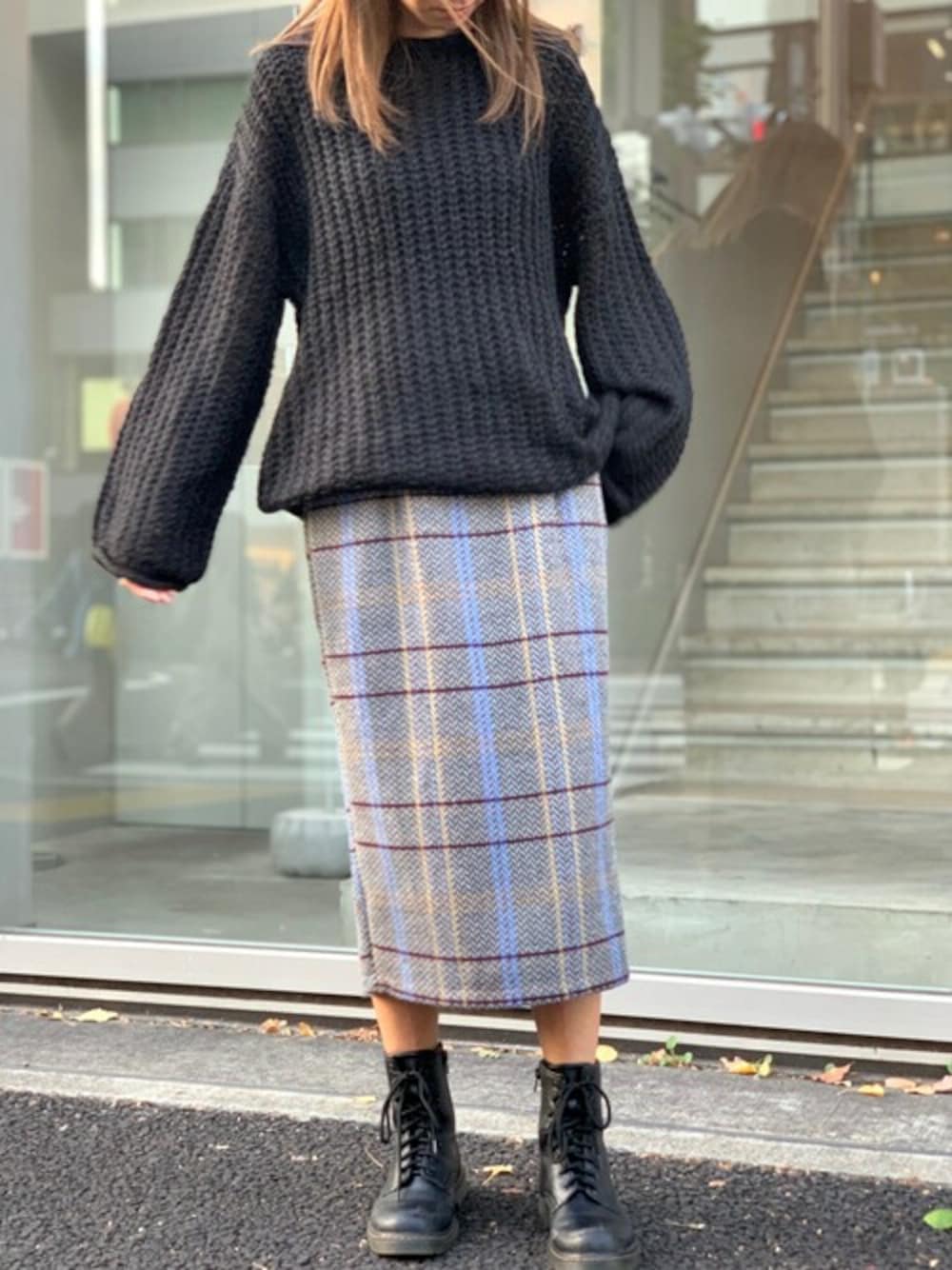 グレー系のスカート、ブラック系のニット/セーターを着用したレディースの冬コーディネートの1枚目の写真