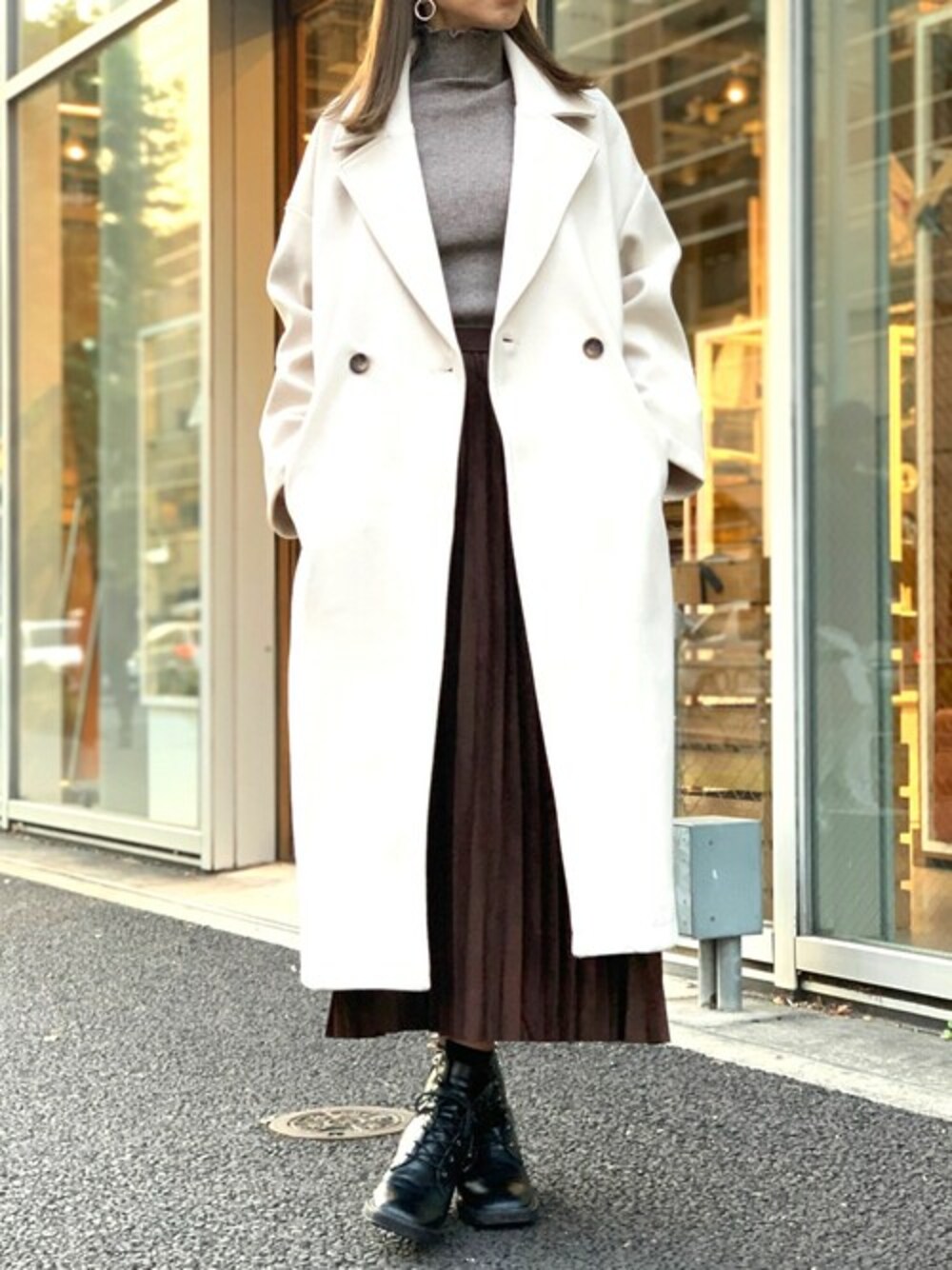 ブラウン系のニット/セーター、ブラック系のブーツ、ホワイト系のチェスターコートを着用したレディースの冬コーディネートの1枚目の写真