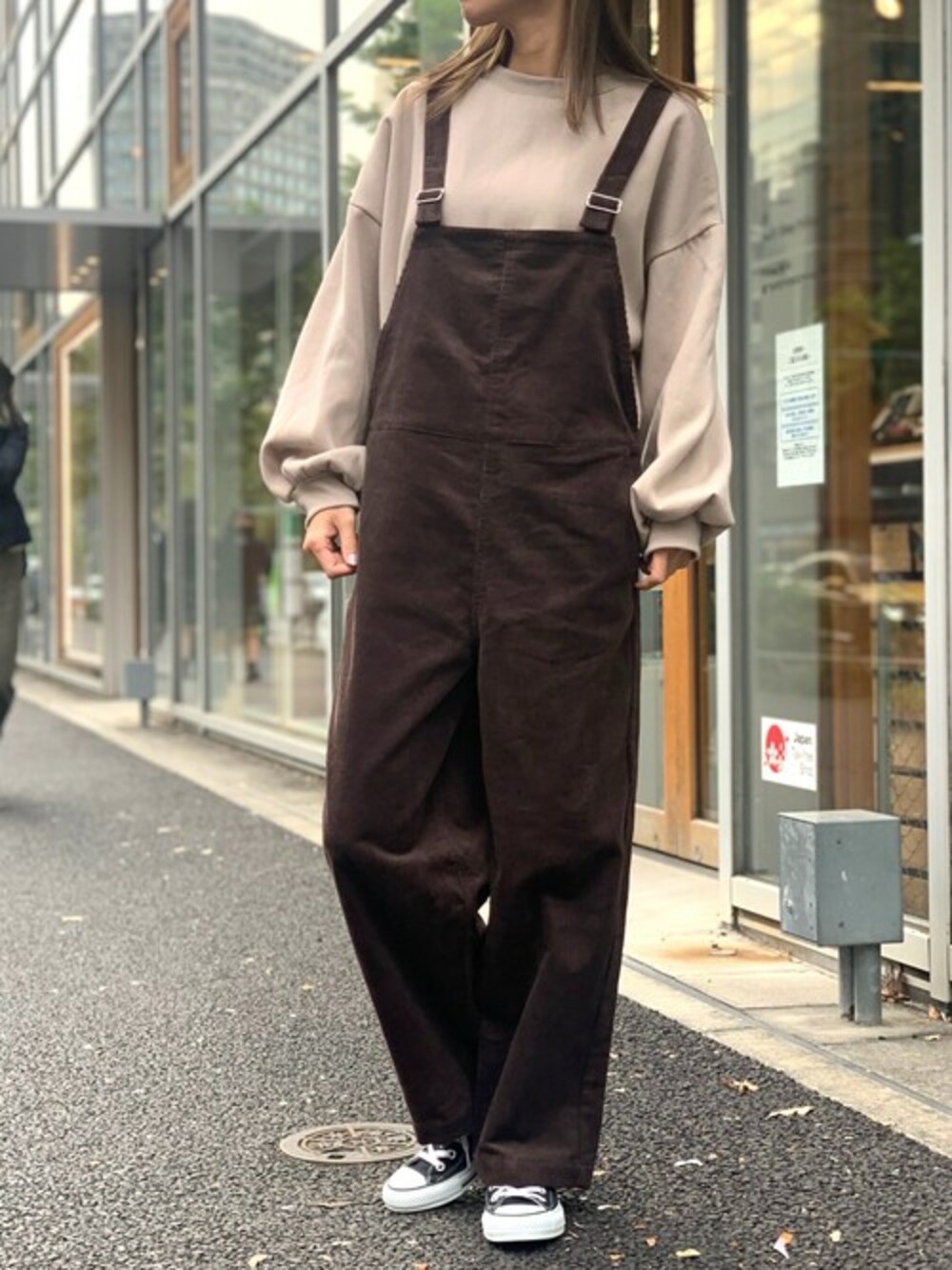 ブラウン系のサロペット/オーバーオール、ブラウン系のスウェット、ブラック系のスニーカーを着用したレディースの冬コーディネートの1枚目の写真