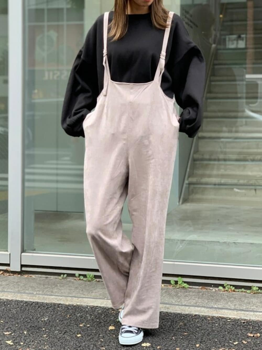 ブラック系のスウェット、ベージュ系のサロペット/オーバーオール、ブラック系のスニーカーを着用したレディースの冬コーディネートの1枚目の写真