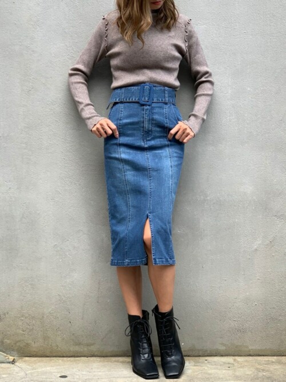 ブラウン系のニット/セーター、ブルー系のデニムスカート、ブラック系のブーツを着用したレディースの冬コーディネートの1枚目の写真