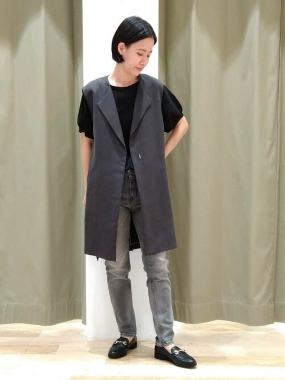 グレー系のワンピース、ブラック系のニット/セーター、ブラック系のデニムパンツを着用したレディースの秋コーディネートの1枚目の写真