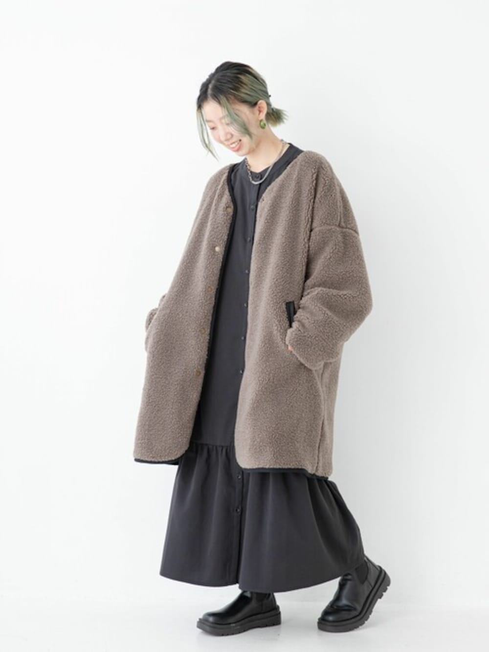 ブラック系のノーカラーコートを着用したレディースの冬コーディネートの1枚目の写真