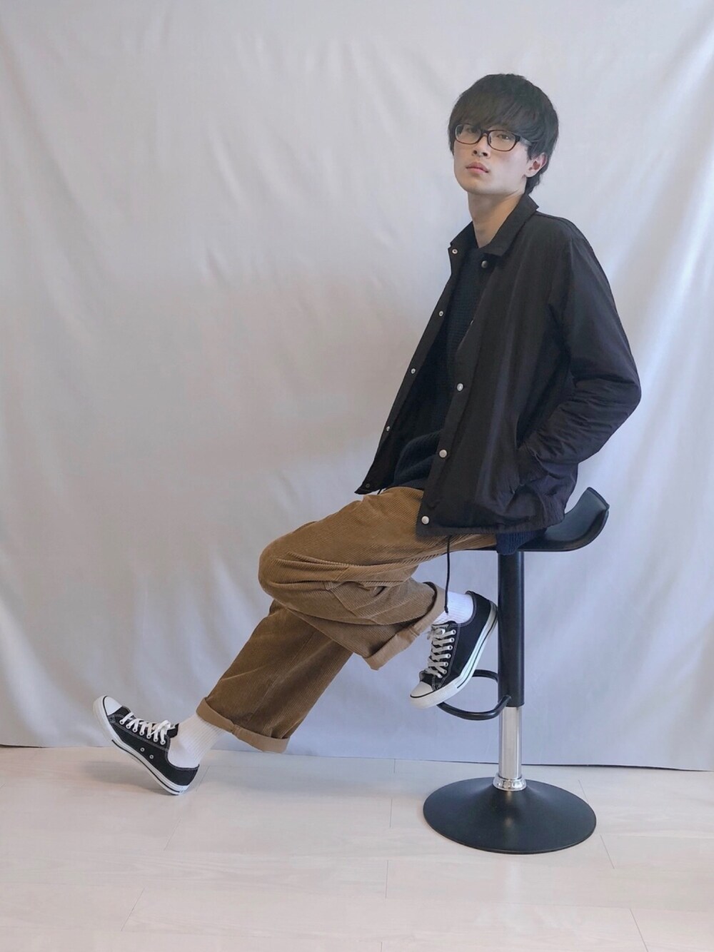 ブラック系のブルゾン、ブルー系のニット/セーター、ブラウン系のパンツを着用したメンズの秋コーディネートの1枚目の写真